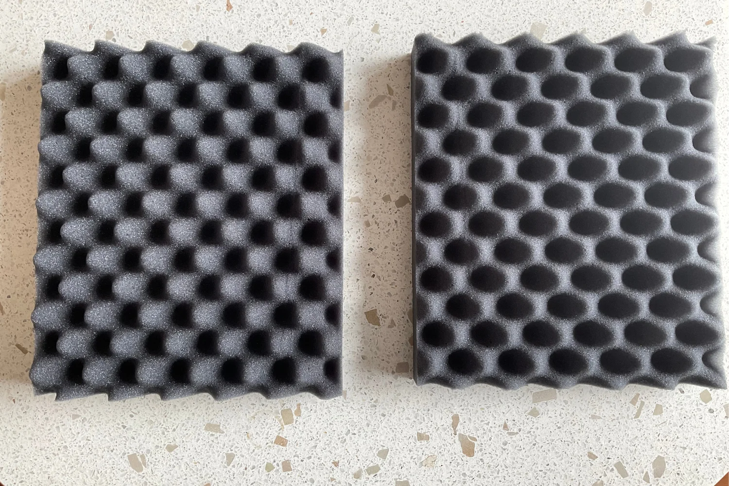 Two black acoustic foam panels with different patterns, one with a pyramid shape and the other with a honeycomb shape.