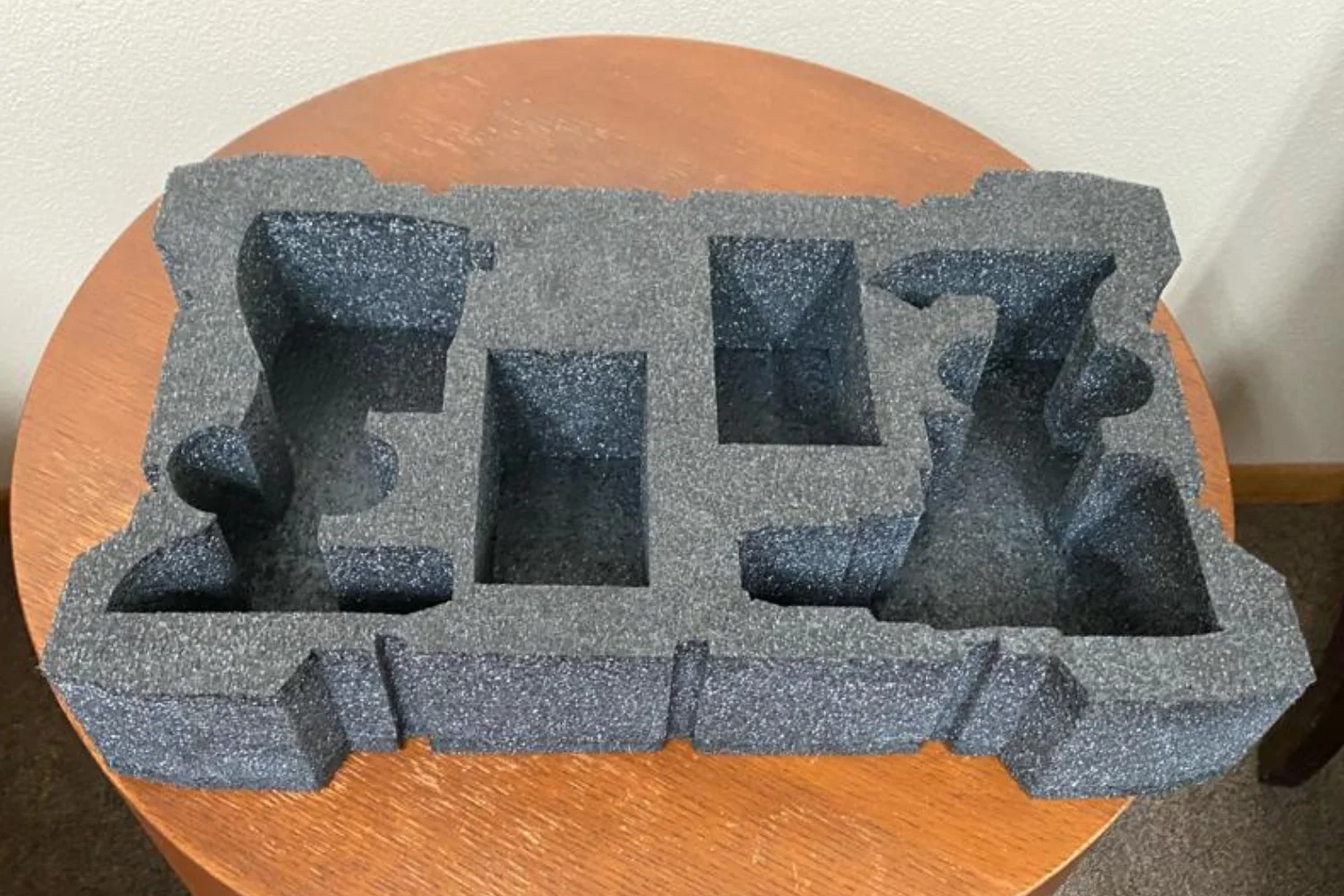 A custom-cut foam packaging tray with multiple compartments and cutouts designed to fit and protect an electronic device.