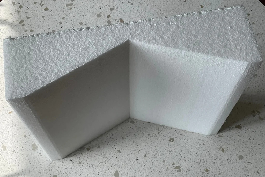A white foam corner protector shaped like an inverted "V" to protect corners from damage during shipping or handling.