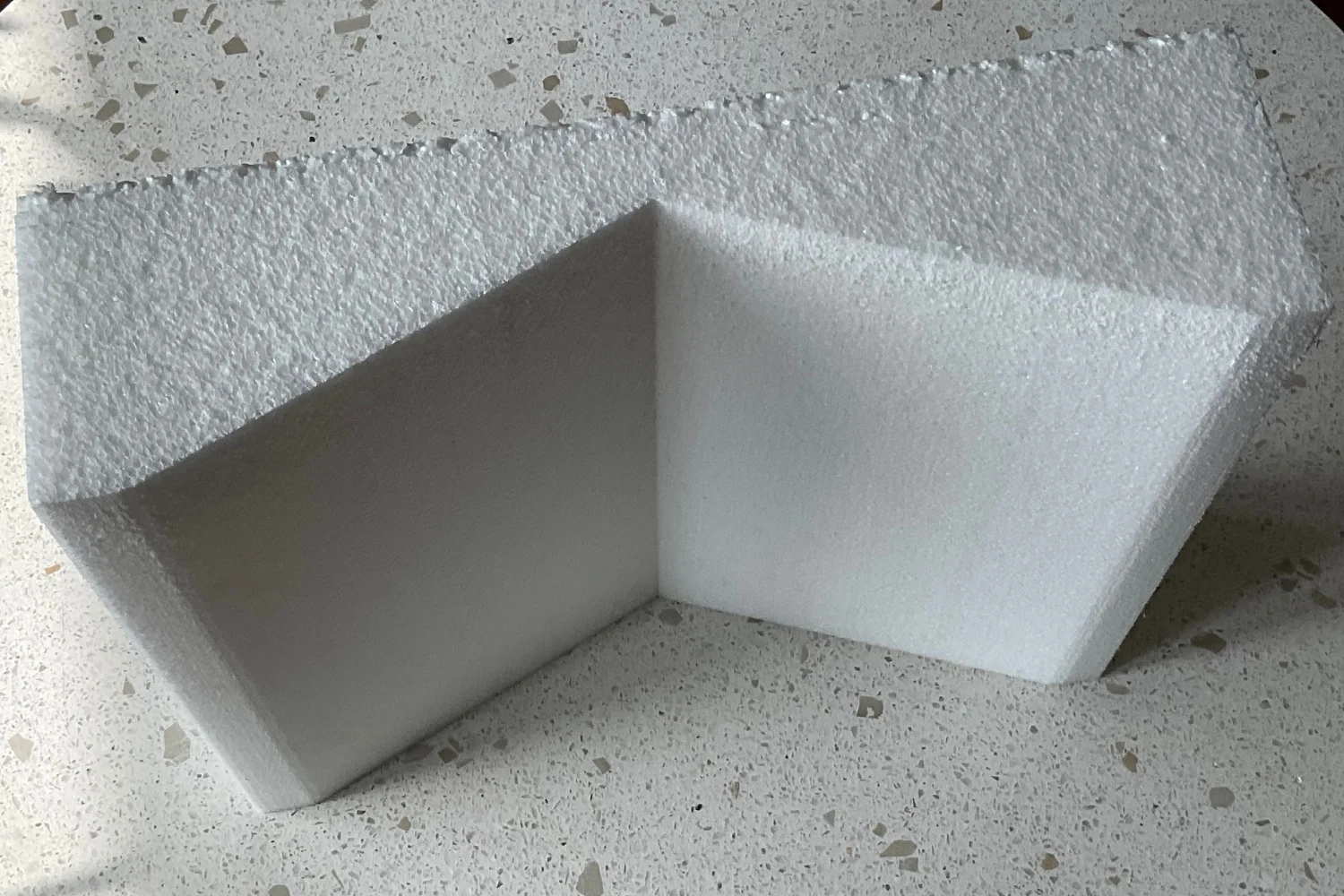 A white foam corner protector shaped like an inverted "V" to protect corners from damage during shipping or handling.