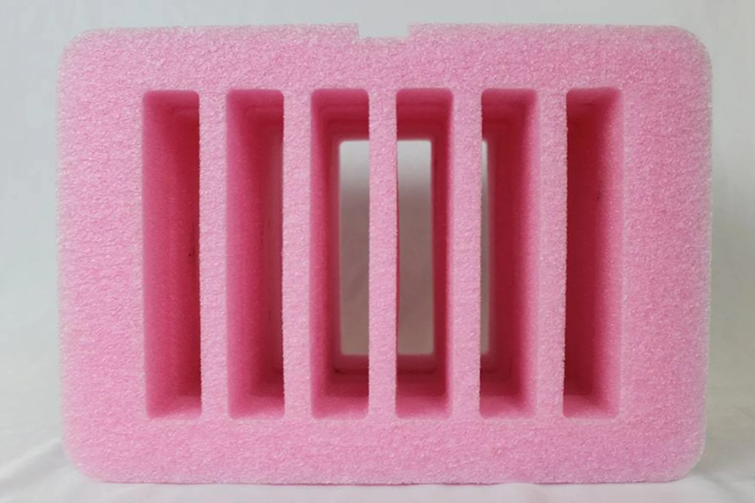 A pink foam packaging tray with multiple rectangular compartments, ideal for storing and protecting small items.